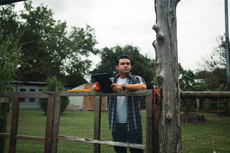 Homem com tablet no campo, rotina ligada ao crédito rural das vagas Cresol